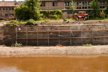 Pravá strana nábřežní zdi po proudu řeky, je postupně očišťována a jsou vyplňovány spáry mezi bloky pískovce.