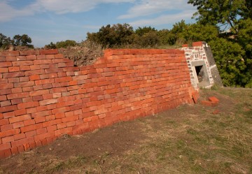 Nově budovaná cihlová opěrná zeď střeleckého postavení na střeše kavalíru 2. Po pravé straně v loňském roce opravené komíny bývalé pevnostní pekárny.